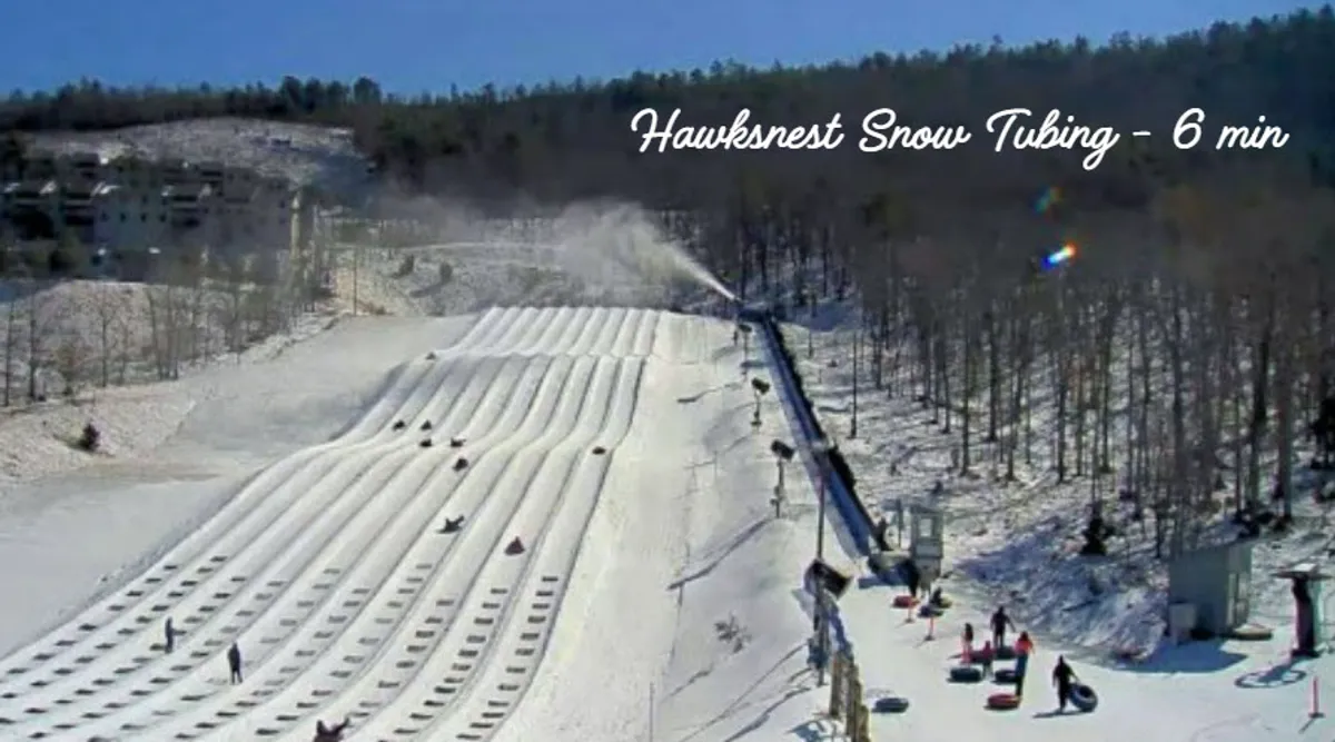 People zip down snow tubing lanes on snow-covered hills, surrounded by a winter landscape. The scene captures the thrill and excitement of family-friendly winter activities, with participants of all ages enjoying the ride.